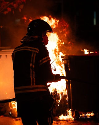 Firefighter in full gear helping a child during a community safety event at sunset.