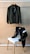 Two jackets are displayed against a plain background. One jacket is hanging on a wooden hanger from a rod while the other is draped over the back of a chair with light wooden legs and white seat. Both jackets appear to have a smooth texture and a similar design with a front zipper closure.
