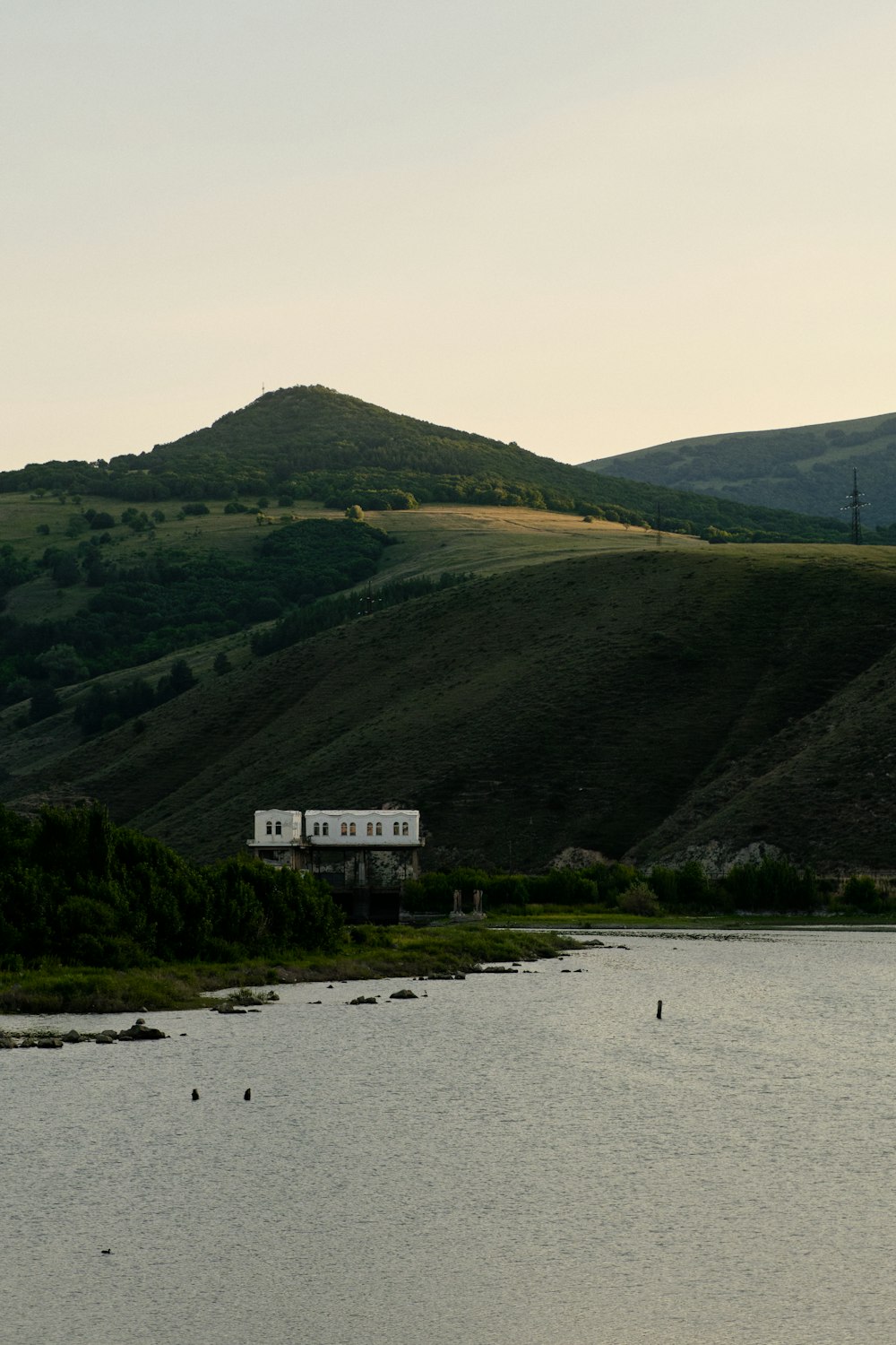 a body of water with a house on a hill in the background