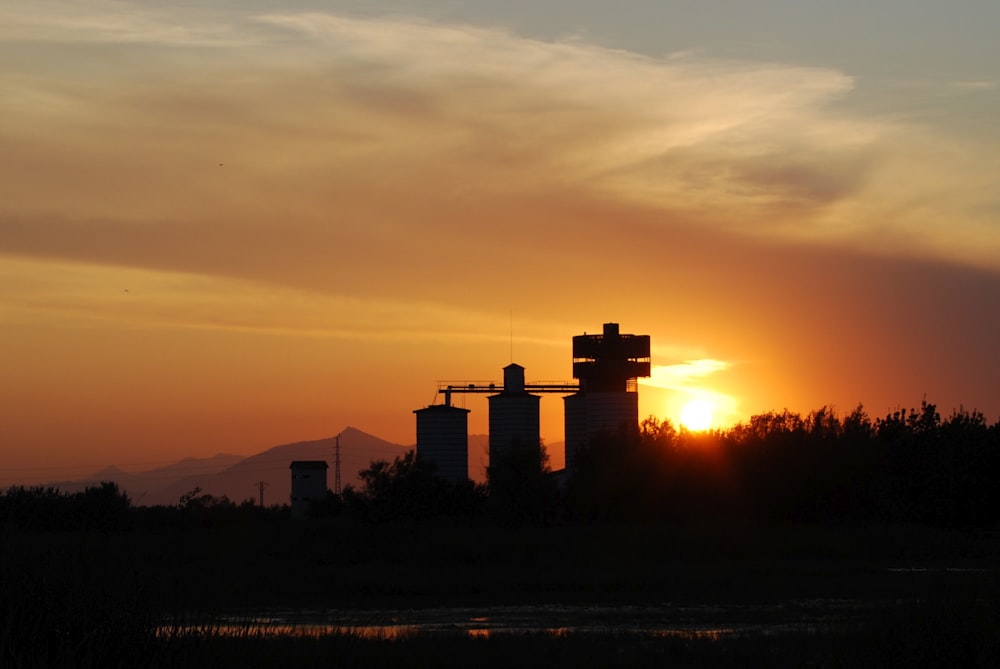 the sun is setting over a farm with silos