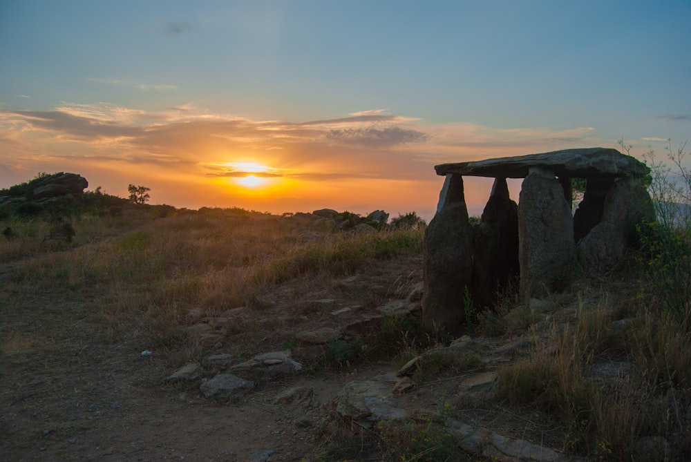 the sun is setting over a rocky outcropping