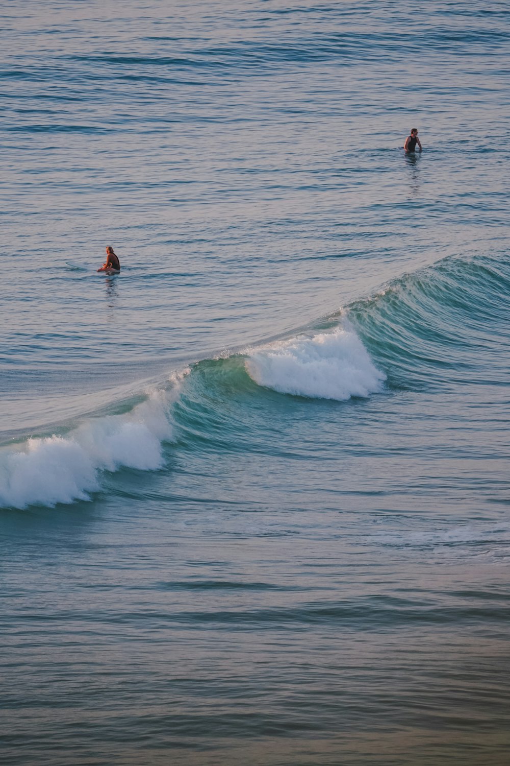 a couple of people riding waves on top of surfboards