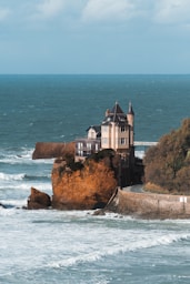 a house sitting on top of a cliff next to the ocean