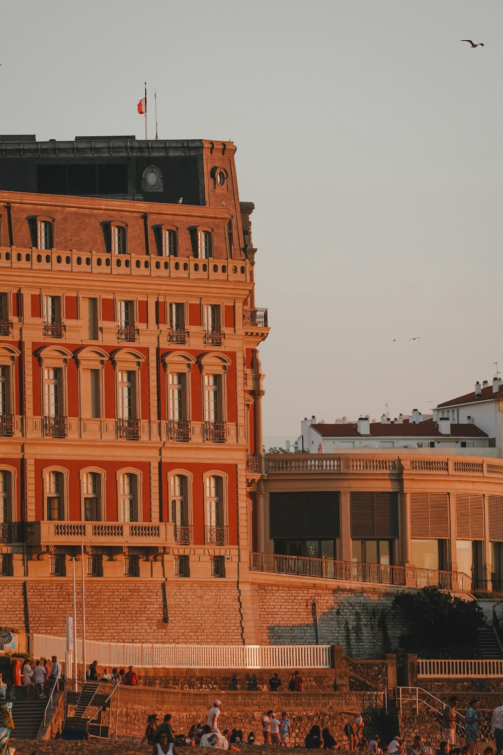 a group of people sitting on a beach in front of a building