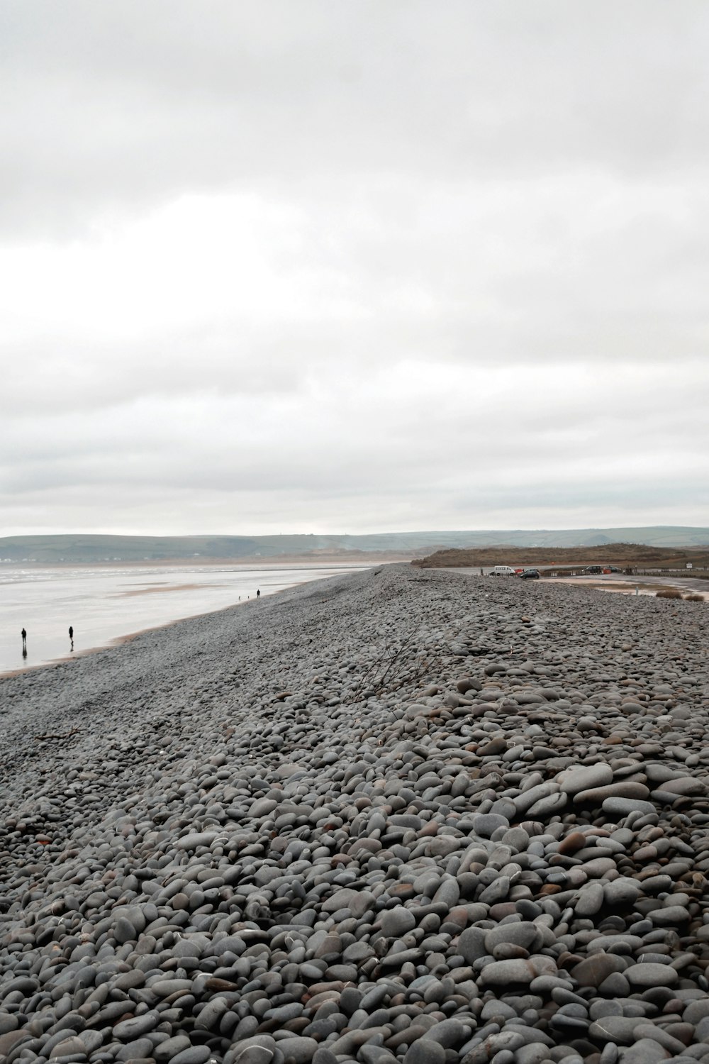 a couple of people standing on top of a rocky beach