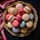 A variety of colorful macarons are artfully arranged on a decorative golden plate. The assortment includes shades of pink, cream, red, purple, and light blue, set against a dark background. A luxurious pink fabric with gold patterns partially drapes the scene, enhancing the elegant presentation.