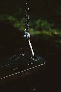 Dark luxury premium leather suspension swing with sleek black metal details in moody lighting