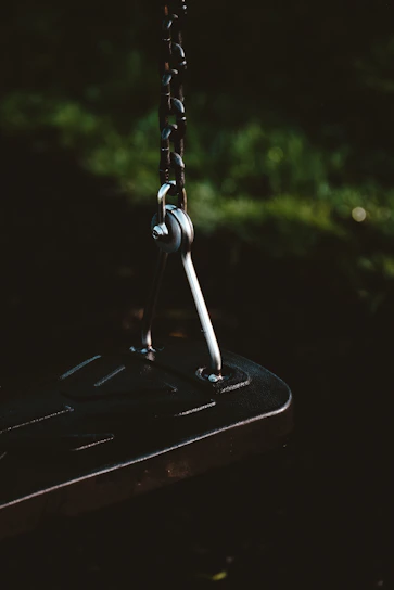 Dark luxury premium leather suspension swing with sleek black metal details in moody lighting