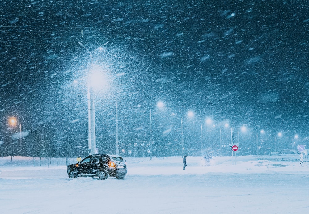 um carro estacionado em uma rua nevada à noite