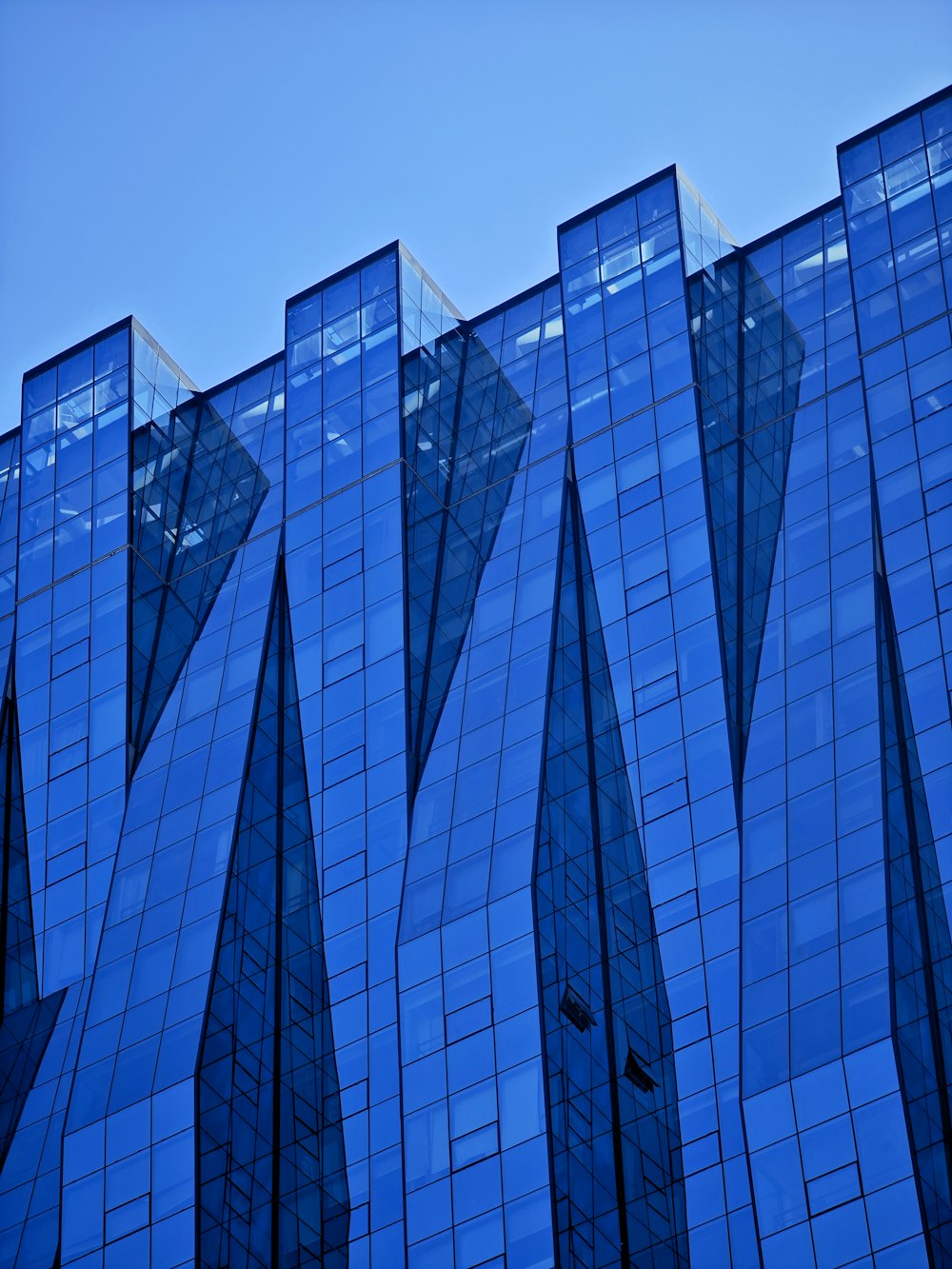 a very tall building with many windows reflecting the sky