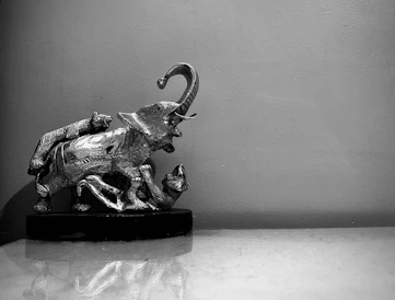 Elegant carved mahogany elephant sculpture resting on a rustic wooden table