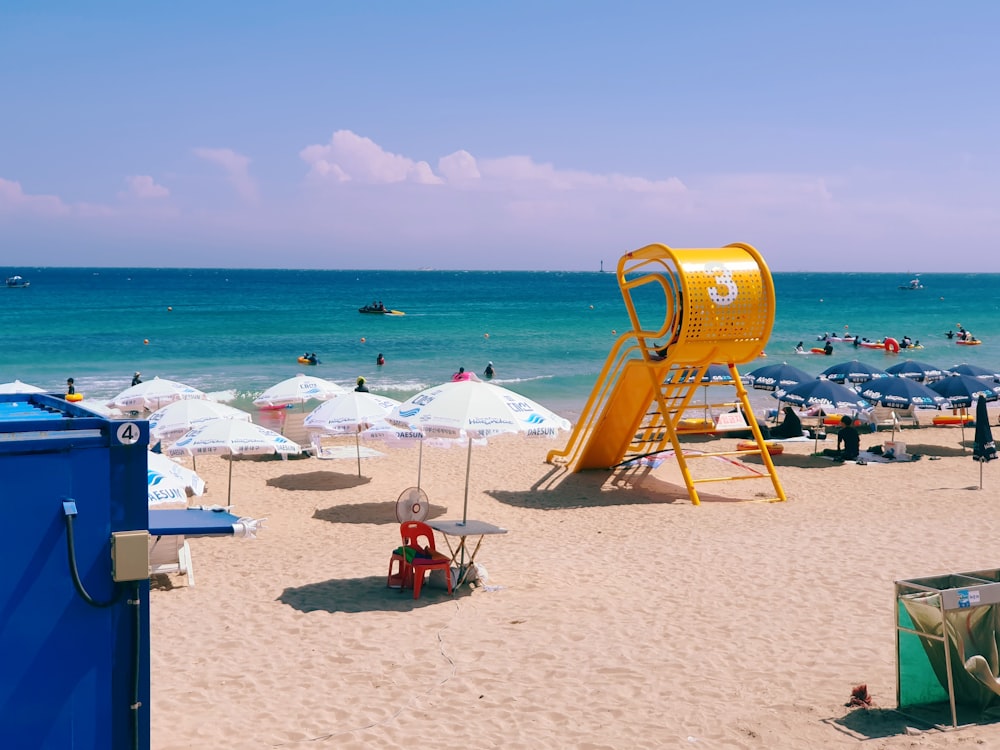 a yellow slide on a beach next to the ocean