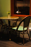 A rustic round café table with a small vase of flowers on top