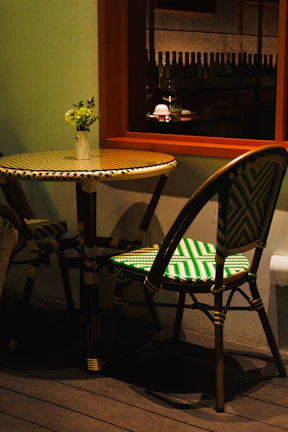 A rustic round café table with a small vase of flowers on top