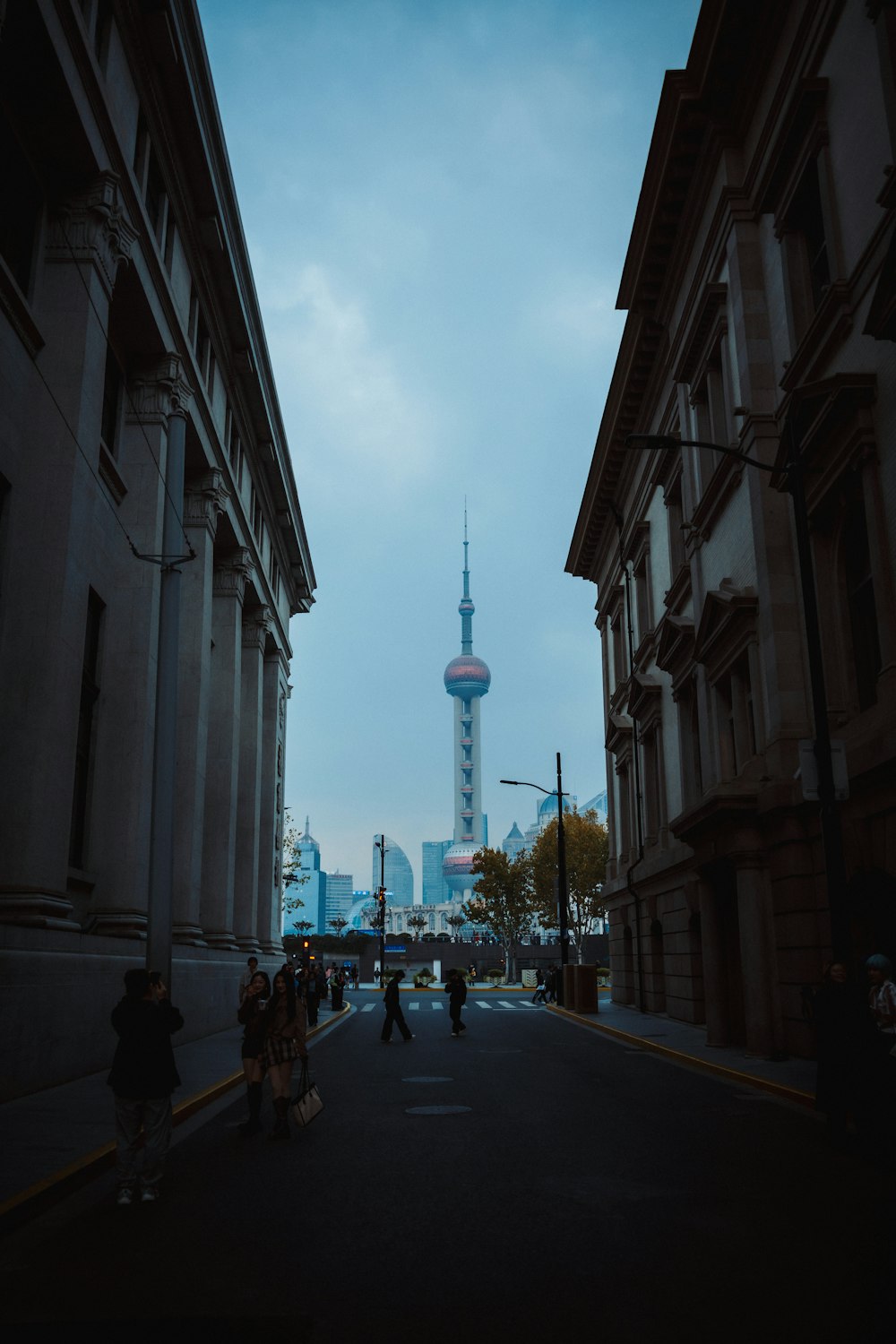 people walking down a street in front of tall buildings