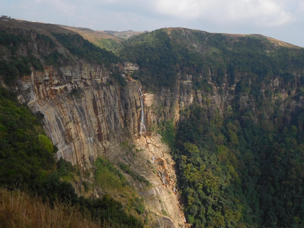 a mountain side with a waterfall in the middle of it