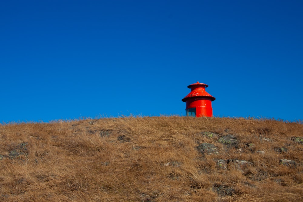 a red light house sitting on top of a hill