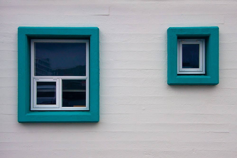 two windows on the side of a white building