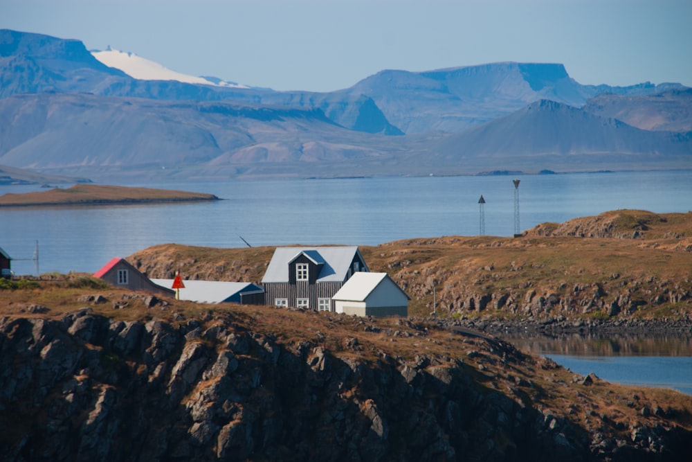 a house sitting on top of a hill next to a body of water