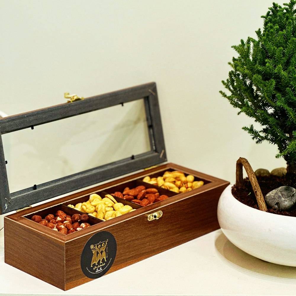 a wooden box filled with nuts next to a potted tree
