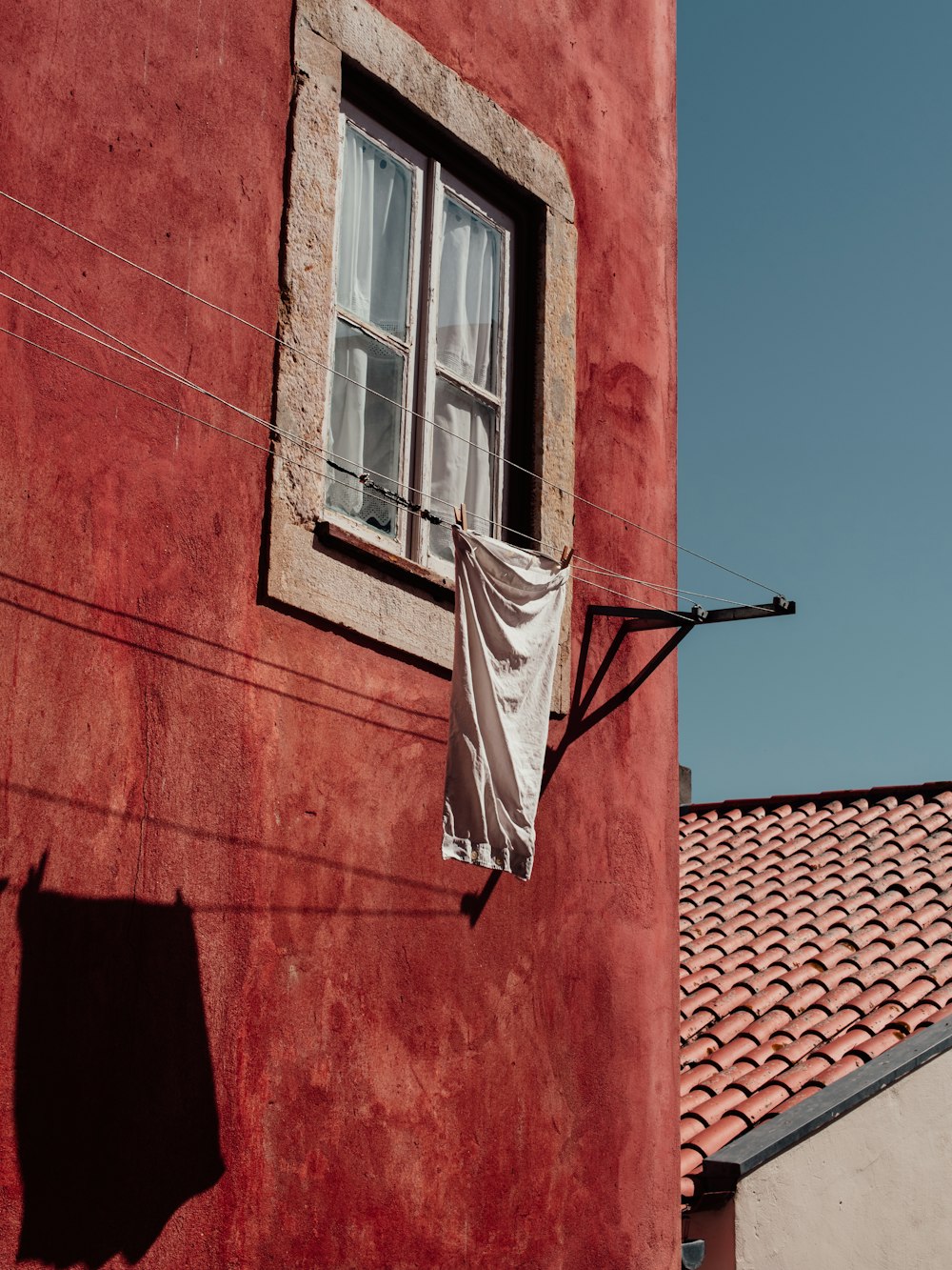 a red building with a window and a white curtain