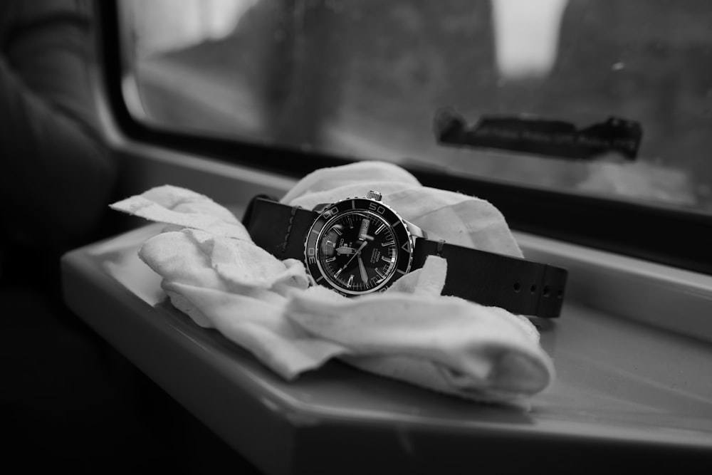 a watch sitting on a napkin on a window sill