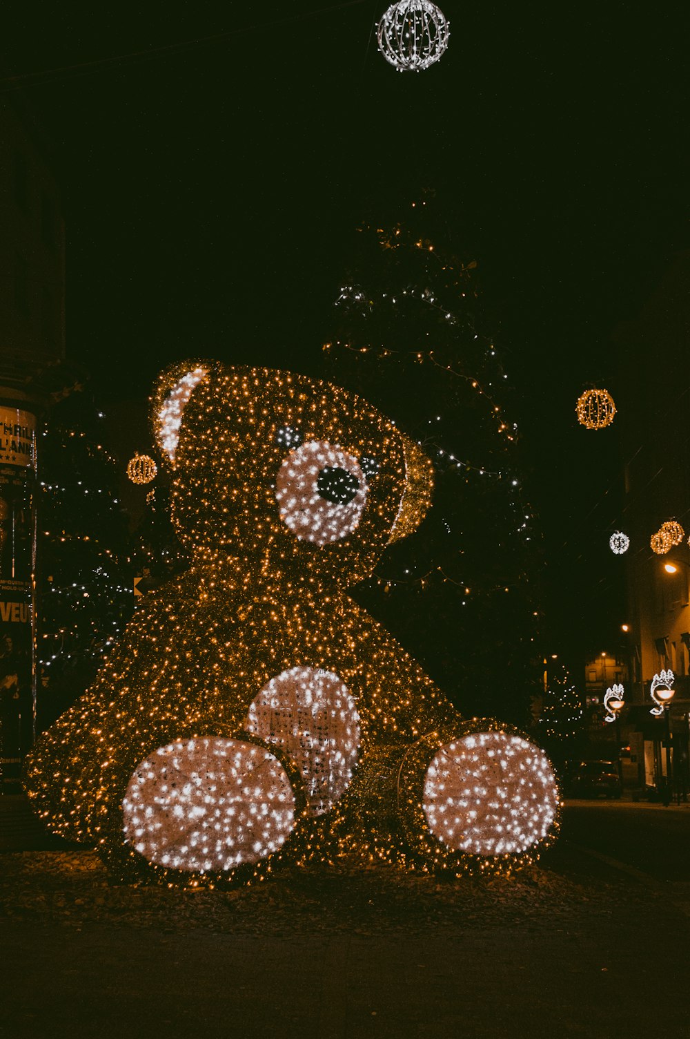 a lighted teddy bear sitting in the middle of a street
