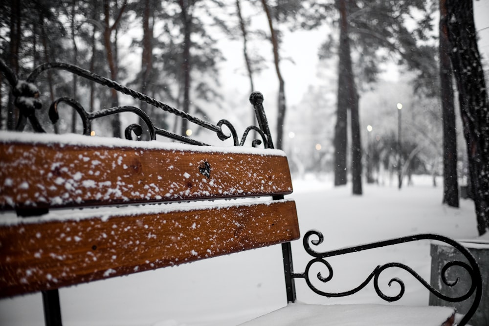 a wooden bench covered in snow in a park