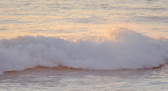 A slow-motion capture of gentle waves lapping against a quiet shore at sunset, evoking peaceful reflection.