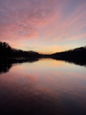 A tranquil lake reflecting pastel skies at sunset, inviting quiet reflection.