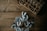 A wooden table surface with a decorative wreath made of grey leaves and berries positioned in the lower part of the image. In the upper right corner, a wooden box with compartments is filled with small decorative items such as acorns and twigs.
