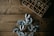 A wooden table surface with a decorative wreath made of grey leaves and berries positioned in the lower part of the image. In the upper right corner, a wooden box with compartments is filled with small decorative items such as acorns and twigs.