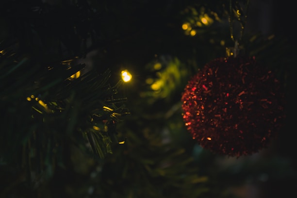 Close-up of unique Christmas ornaments hanging on a beautifully decorated tree, glowing gently.