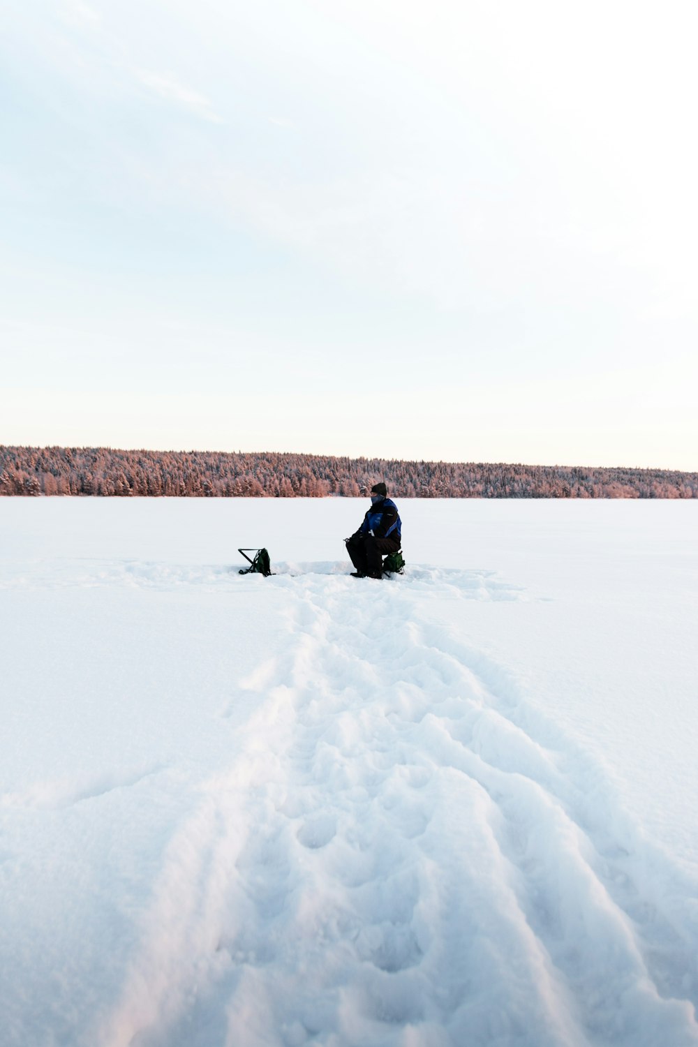 a person sitting in the middle of a snowy field