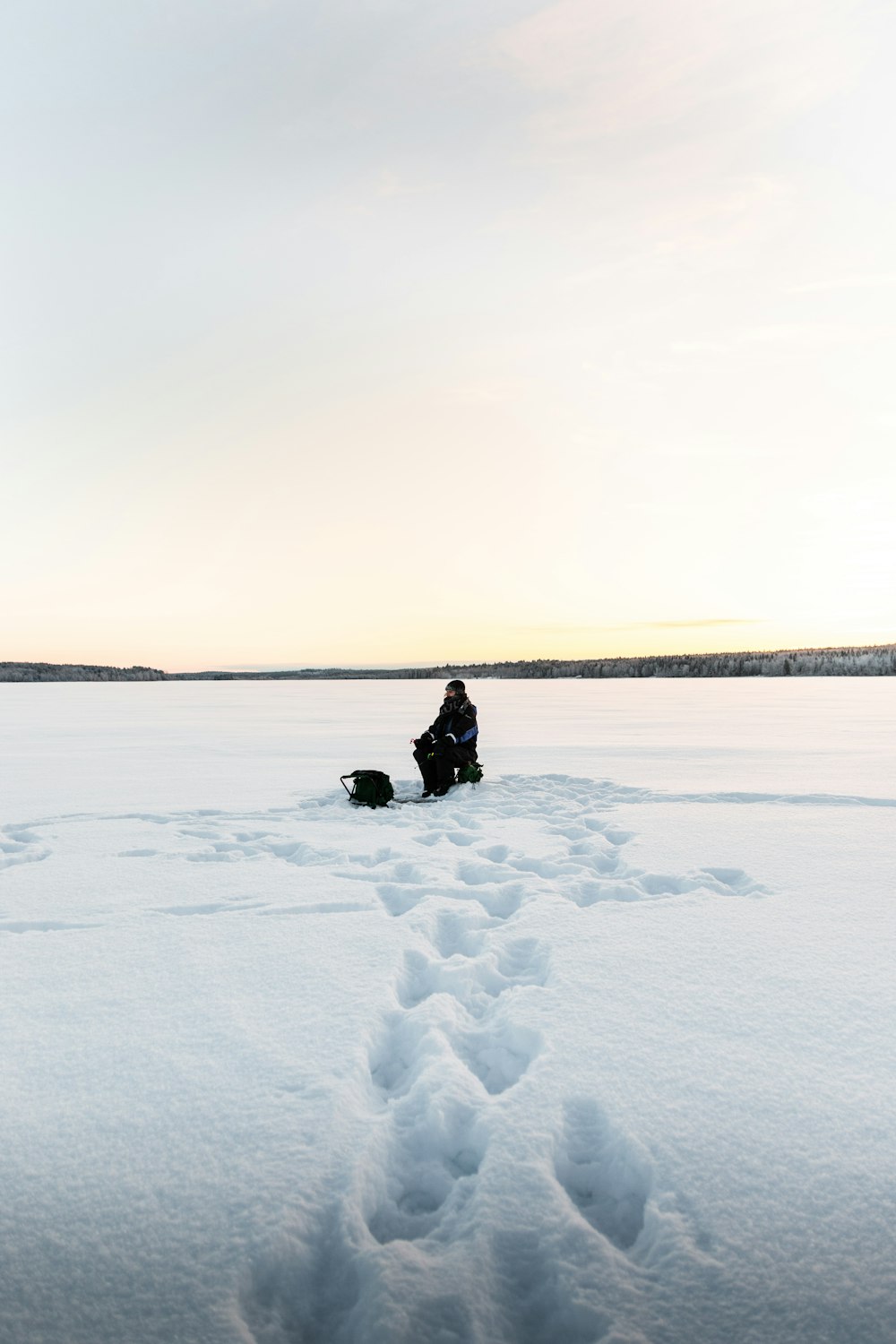a person sitting in the middle of a snowy field