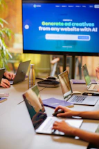 a group of people sitting around a table with laptops
