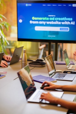 a group of people sitting around a table with laptops