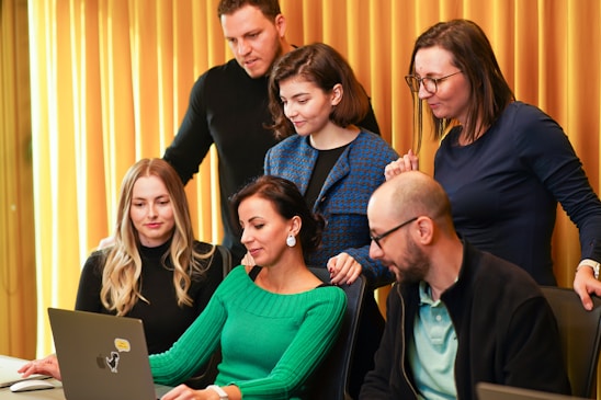 a group of people sitting around a laptop computer