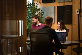 a group of people sitting around a table with laptops