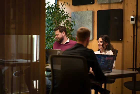 a group of people sitting around a table with laptops