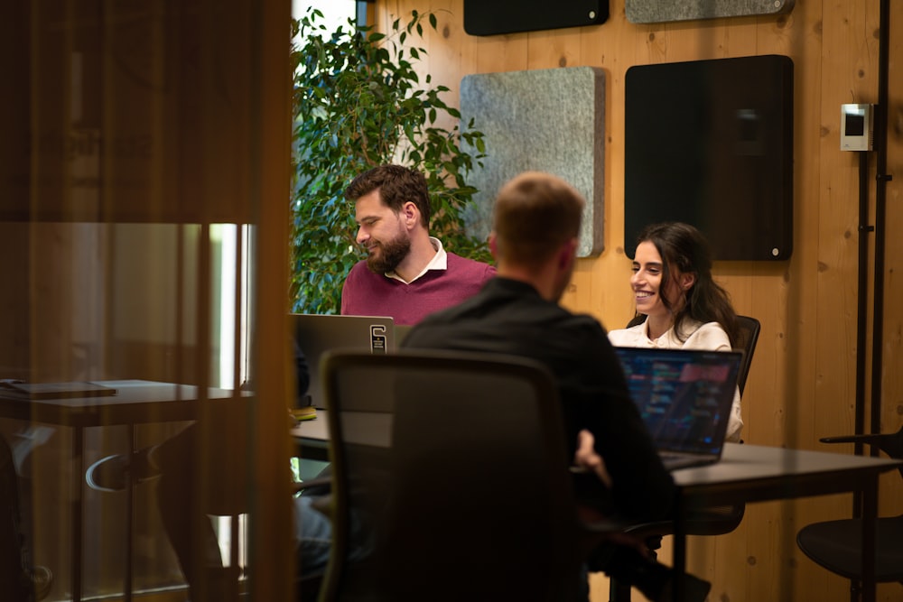 a group of people sitting around a table with laptops