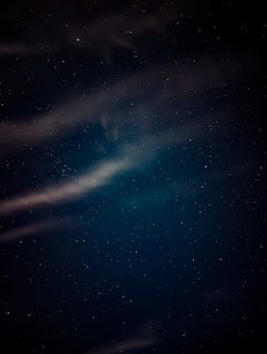 A serene night sky filled with stars, casting a soft glow over a tranquil landscape.