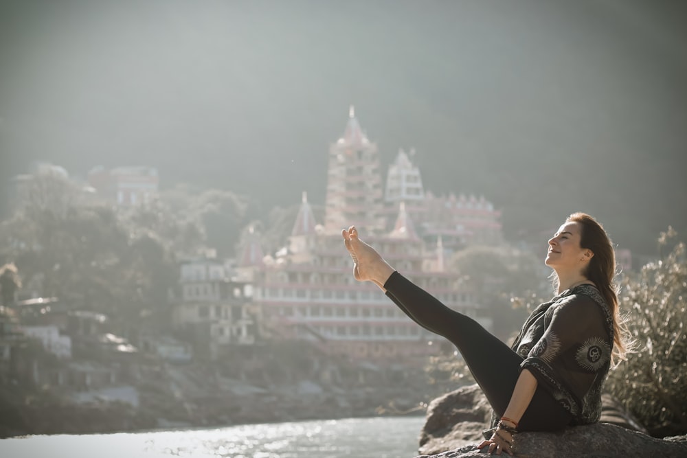 a woman sitting on top of a rock next to a river