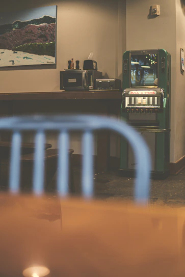 A modern vending machine with glowing electric green accents in a stylish office breakroom.