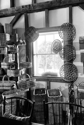 Artisan woven basket filled with colorful cushions in a bright sunlit room.