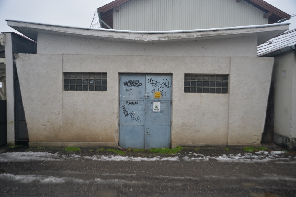 a white building with a blue door and graffiti on it