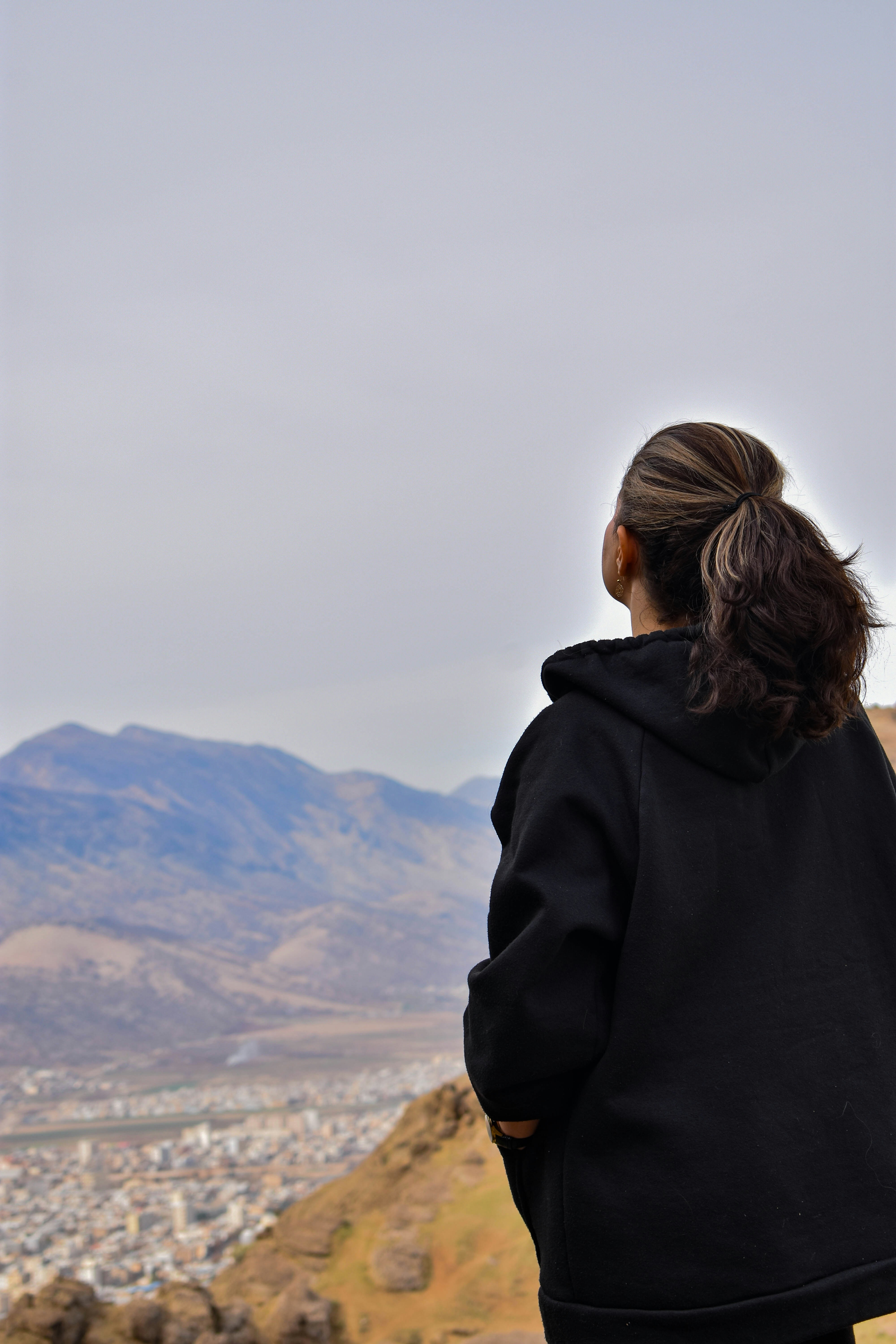 a woman standing on top of a hill overlooking a city