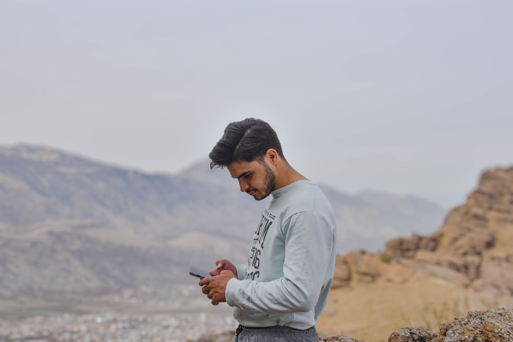 a man sitting on a rock looking at his cell phone