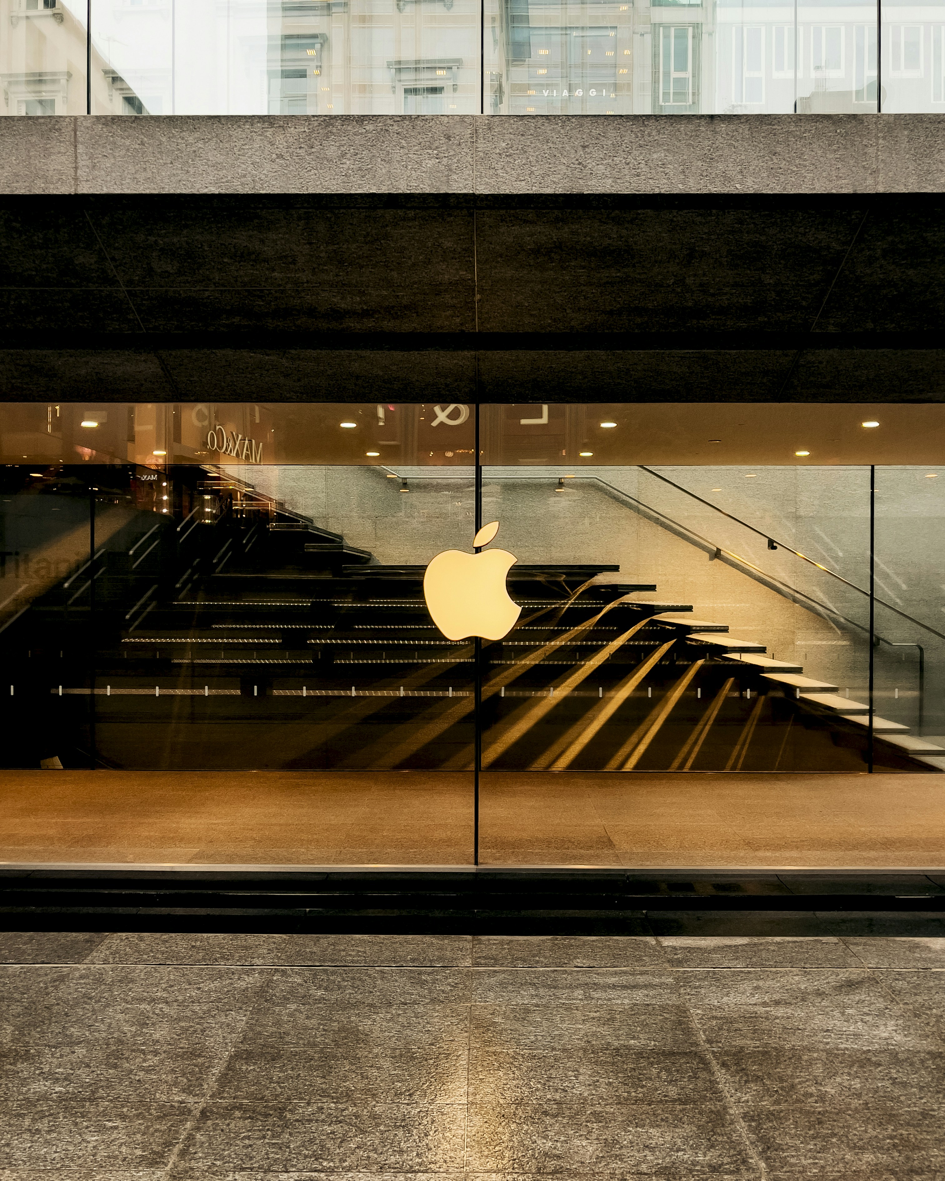 an apple logo is reflected in the glass of a building