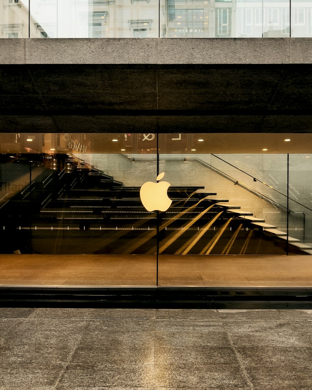 an apple logo is reflected in the glass of a building